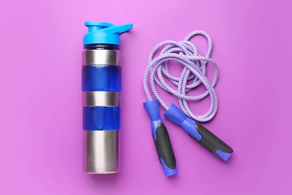 Sports water bottle and jumping rope on color background — Stock Photo, Image