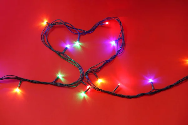 Серце з різдвяних вогнів на кольоровому фоні — стокове фото