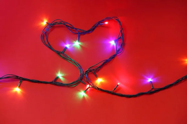 Coeur fait de lumières de Noël sur fond de couleur Images De Stock Libres De Droits