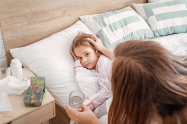 Anne evde grip olan küçük kızı ile ilgileniyor