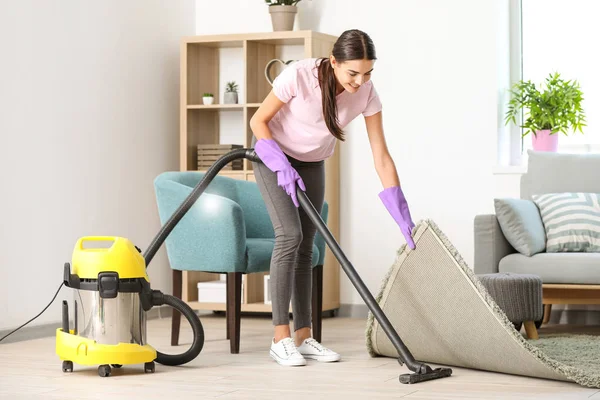 Young woman hoovering floor in flat — Stock Photo, Image