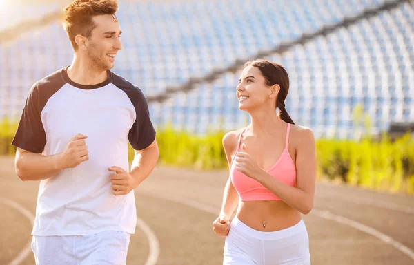 Sporty young couple running at the stadium — Stock Photo, Image