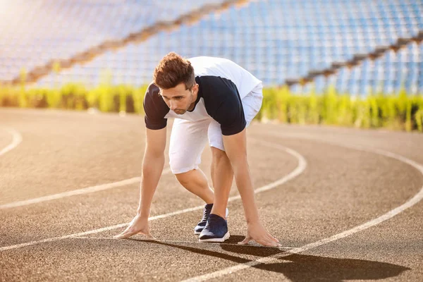 Sporty young man in crouch start position at the stadium — Stock Photo, Image