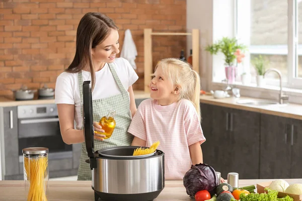 Woman and her little daughter using modern multi cooker in kitchen — Stock Photo, Image