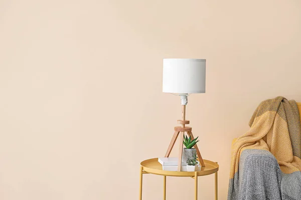 Lamp with books and plants near light wall in room