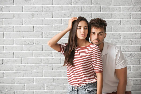 Fashionable young couple against brick wall — Stock Photo, Image