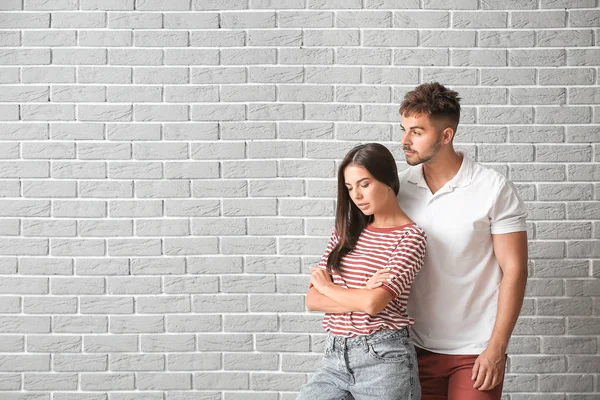 Fashionable young couple against brick wall — Stock Photo, Image