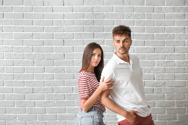 Fashionable young couple against brick wall — Stock Photo, Image