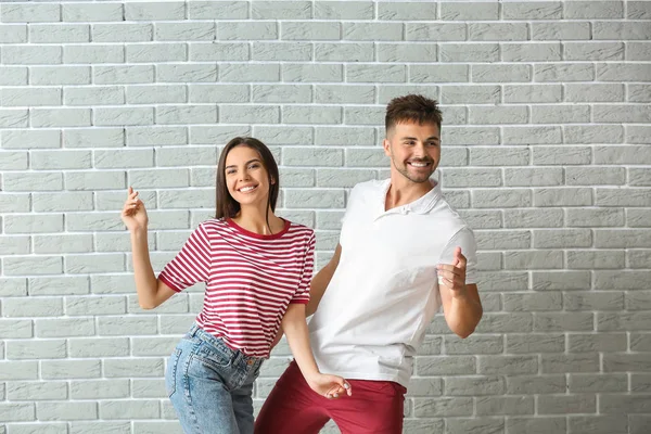 Pareja joven de moda contra la pared de ladrillo — Foto de Stock