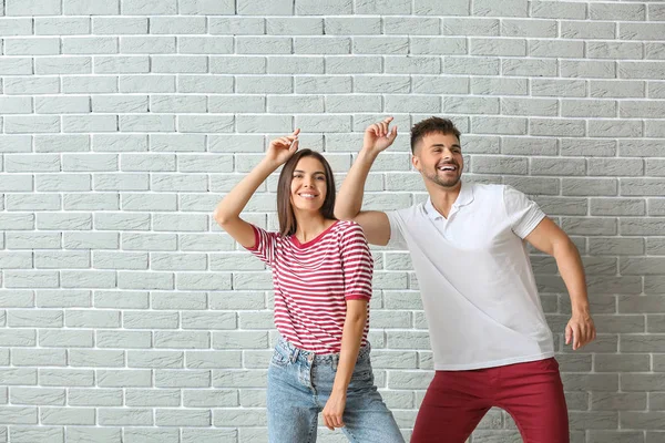 Fashionable young couple against brick wall — Stock Photo, Image