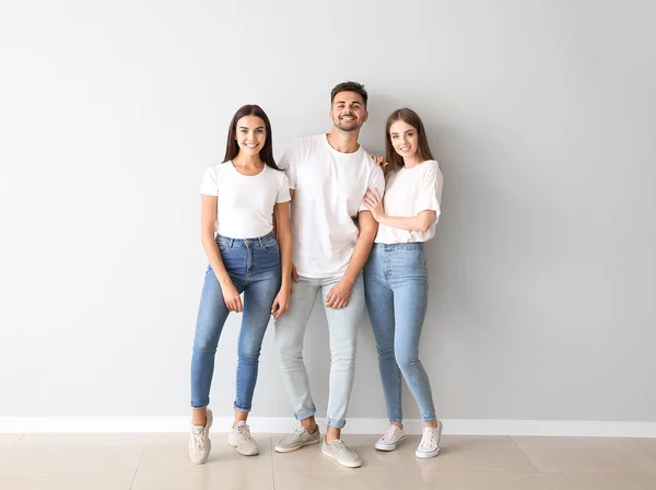 Grupo de jóvenes en ropa casual con estilo cerca de la pared de luz — Foto de Stock