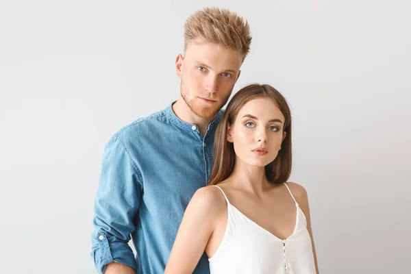 Ungt par i snygga casual kläder på ljus bakgrund — Stockfoto