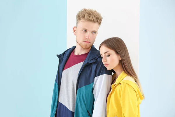 Young couple in stylish sportswear on color background — Stock Photo, Image