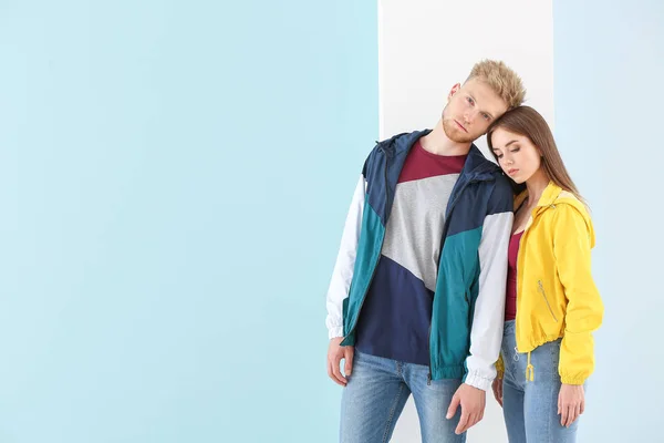 Young couple in stylish sportswear on color background — Stock Photo, Image