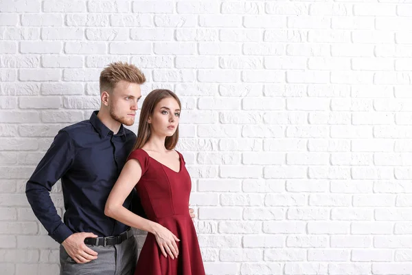 Elegante pareja joven contra la pared de ladrillo blanco — Foto de Stock