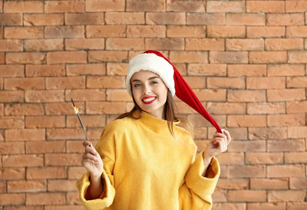 Hermosa mujer joven con chispas de Navidad sobre fondo de ladrillo —  Fotos de Stock