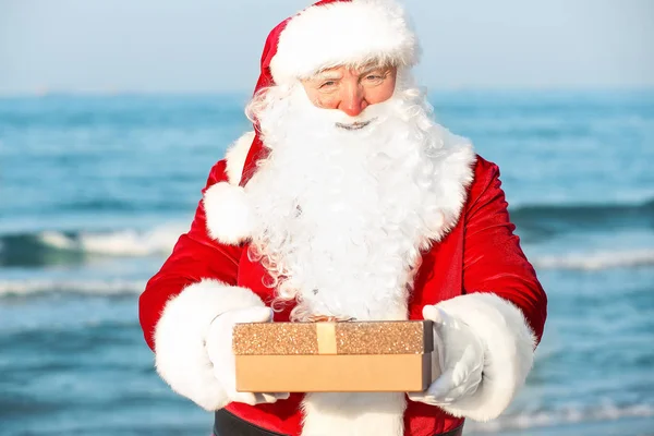 Дід Мороз з подарунковою коробкою в море курорт — стокове фото