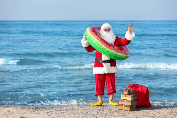 Papai Noel com presentes e anel inflável no resort do mar — Fotografia de Stock