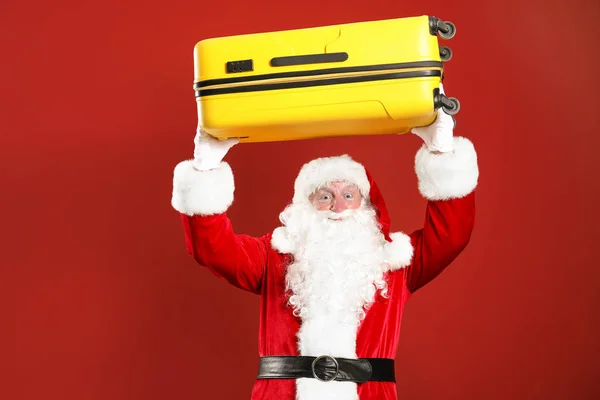 Santa Claus with luggage on color background — Stock Photo, Image