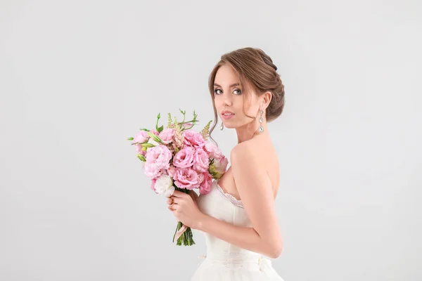 Retrato de hermosa novia joven con ramo de boda sobre fondo claro —  Fotos de Stock