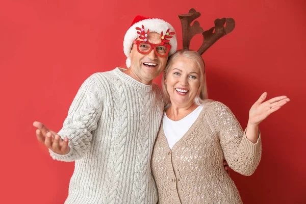 Retrato de casal maduro feliz com decoração de Natal em fundo de cor — Fotografia de Stock