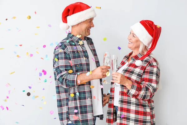 Porträtt av Happy äldre par i jultomten hattar och med glas champagne på vit bakgrund — Stockfoto