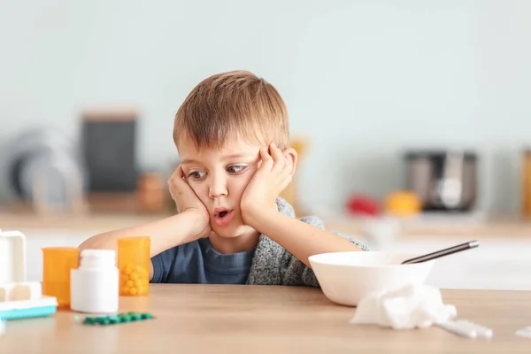 生病的小男孩坐在厨房的桌子旁 — 图库照片