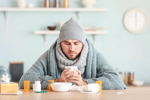 Nemocný muž sedící na kuchyňském stole — Stock fotografie