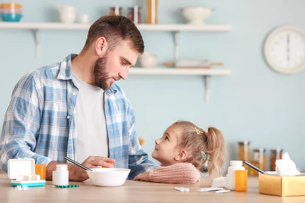 Father feeding his sick daughter with chicken soup in kitchen — Stock Photo, Image