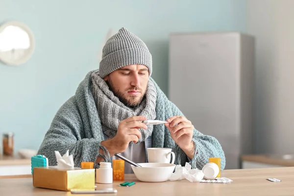 Больной человек измеряет температуру дома — стоковое фото