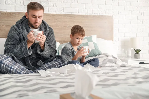 Far och hans lille son sjuk med influensa hemma — Stockfoto