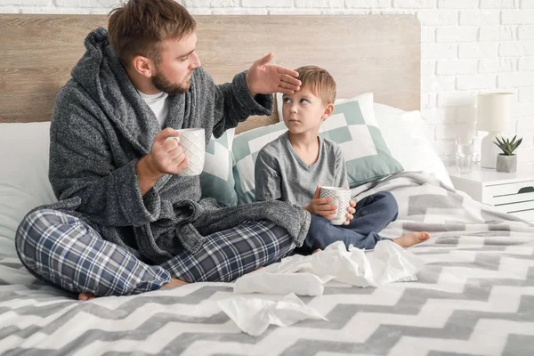 Far och hans lille son sjuk med influensa hemma — Stockfoto