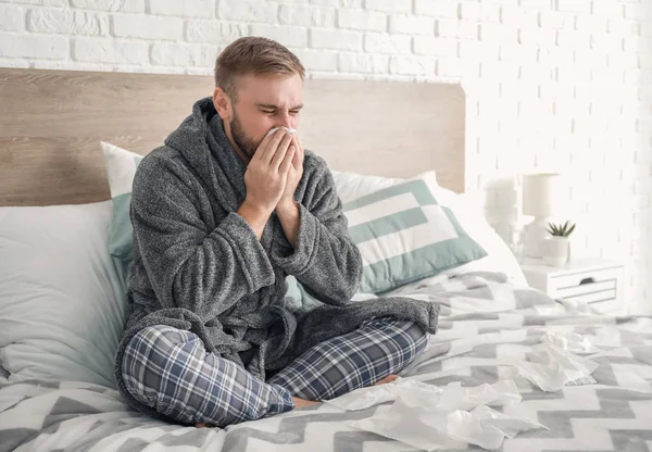 Hombre enfermo de gripe sentado en la cama — Foto de Stock