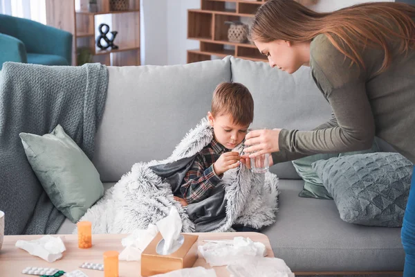 Mor som ger medicin till sin son sjuk i influensa hemma — Stockfoto