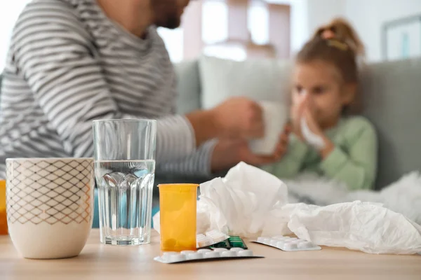 Medicinali sul tavolo e padre offuscato prendersi cura della figlia malata sullo sfondo — Foto Stock