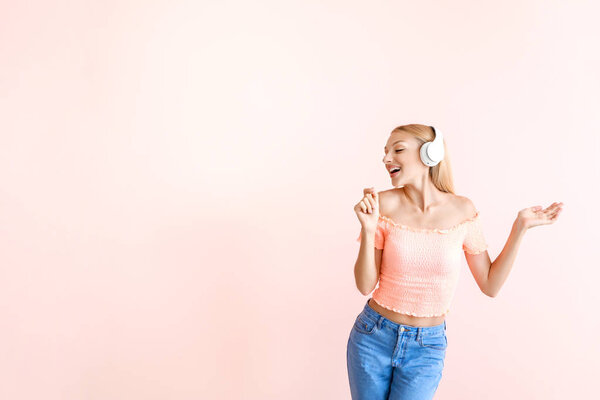 Beautiful young woman listening to music on color background
