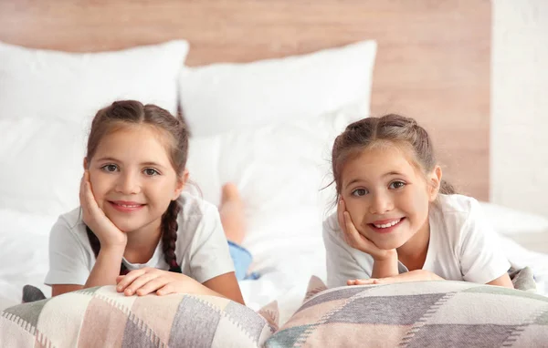 Portrait of cute twin girls lying on bed at home — Stock Photo, Image