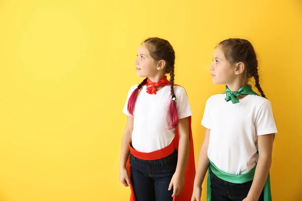 Portret van tweeling meisjes gekleed als superhelden op kleur achtergrond — Stockfoto