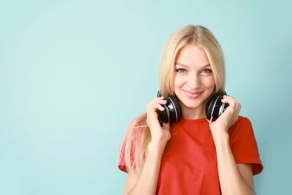 Beautiful young woman with headphones on color background — Stock Photo, Image