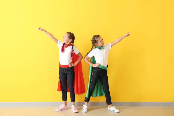 Portrait of twin girls dressed as superheroes near color wall — Stock Photo, Image