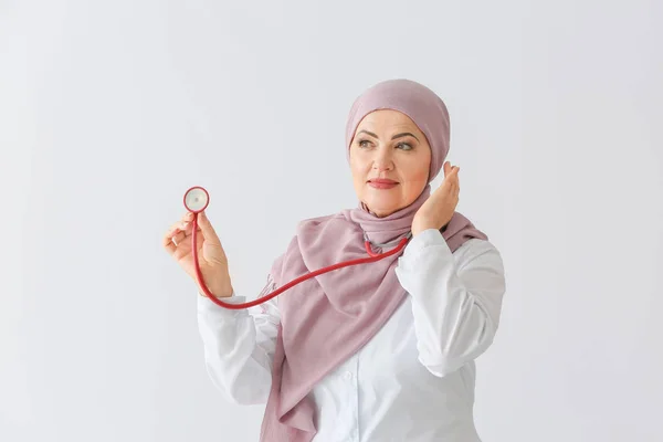 Gyönyörű érett muszlim orvos sztetoszkóppal a fény háttér — Stock Fotó