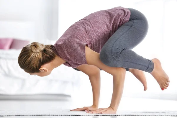 Mujer joven practicando yoga en el dormitorio —  Fotos de Stock