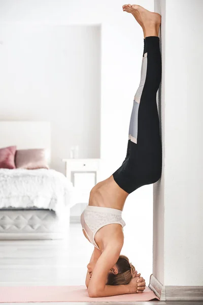 Mujer joven practicando yoga en el dormitorio — Foto de Stock