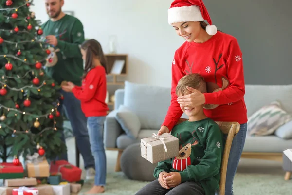 Mother giving Christmas present to her little son at home