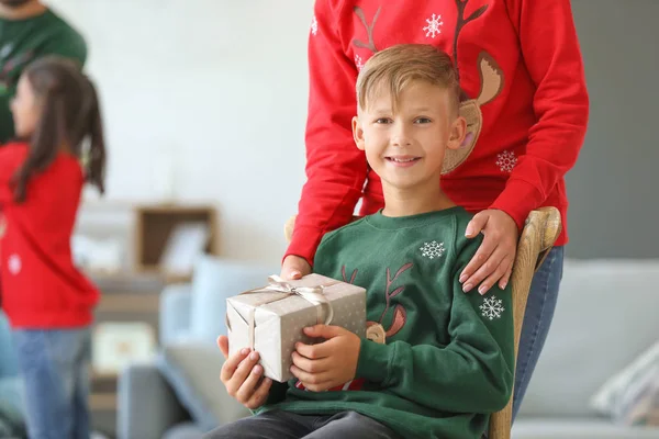 Mother giving Christmas present to her little son at home