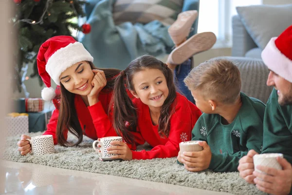 Familia feliz bebiendo chocolate caliente en casa en Nochebuena —  Fotos de Stock