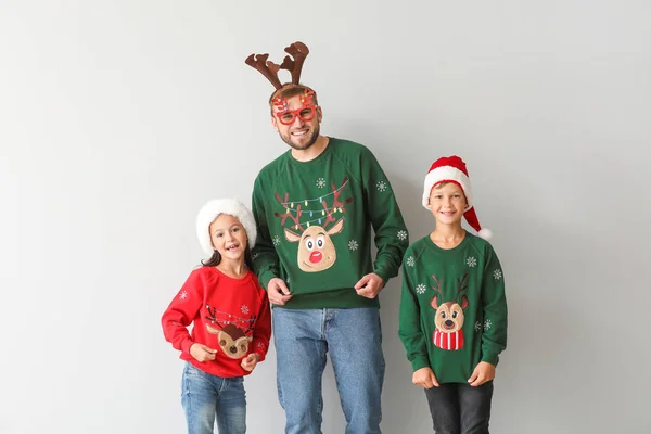 Смішний чоловік і його діти в різдвяних светрах на світлому фоні — стокове фото