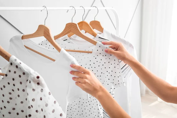 Femme près de rack avec des vêtements suspendus à l'intérieur — Photo