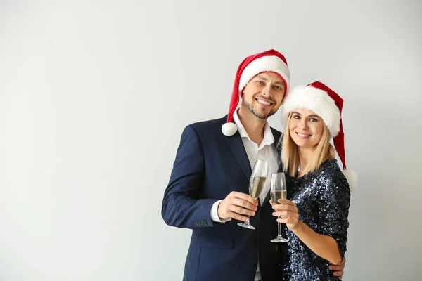 Feliz casal em Santa chapéus beber champanhe no fundo claro — Fotografia de Stock