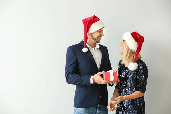 Hombre dando a su esposa regalo de Navidad sobre fondo claro — Foto de Stock